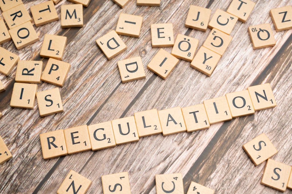 scrabble-letters-spelling-the-word-regulation-19813733 Wooden letter tiles spelling Regulation on a textured wood background, conveying themes of compliance and structure.